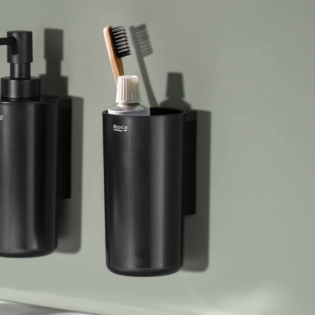 Lifestyle image of the Roca Sonata Matt Black Wall-Mounted Tumbler Holder mounted on a wall next to a soap dispenser
